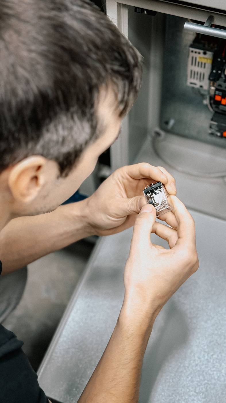 Technician inspecting control components inside HVAC equipment